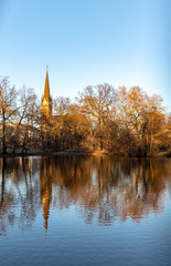Fototapeta na wymiar Teich im Park mit Romantischen Brücken,Kirche im Winter in Leipzig mit blauen Himmel