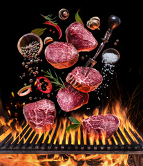 Steak cooking. Conceptual picture. Steak with spices and cutlery under burning grill grate. - obrazy, fototapety, plakaty