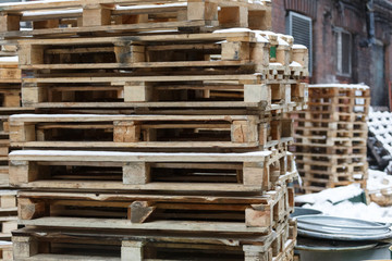 Cropped shot of used wooden pallets for transportation of goods, collected in one stack and waiting recycling/soft focus, territory of an industrial factory, ecological concept.