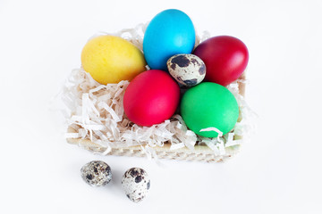 Fototapeta na wymiar Multi-colored Easter eggs lie in a basket on a white background. Yellow, red, green and quail eggs in a basket.