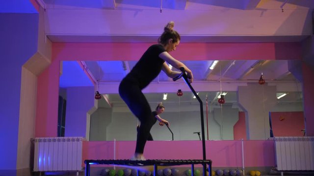 JUMPING FITNESS: A beautiful girl jumping on a fitness trampoline. Slender girl performs exercises on trampolines. Fitness exercises for a beautiful and slim figure