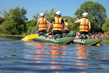 Group of men and women, enjoy water rafting activity at river. Rafting family on holidays. Rafting...
