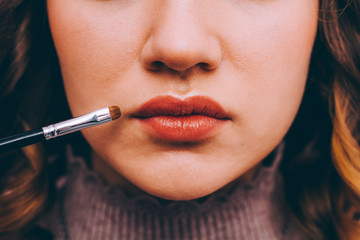 Lips close up. Makeup artist paints lips with lipstick model