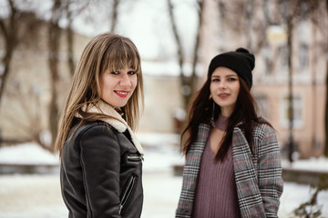 Obraz premium Two young trendy women in snowy winter park