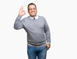 Naklejka premium Middle age bussines arab man wearing glasses over isolated background smiling positive doing ok sign with hand and fingers. Successful expression.