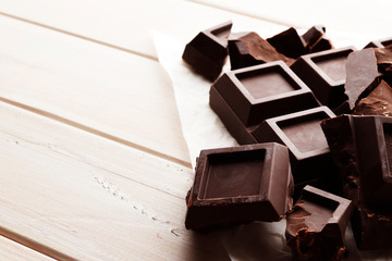 A large bar of black chocolate on a white wooden background with space for text.