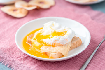 Breakfast, poached egg, bread and cheese on a white plate.