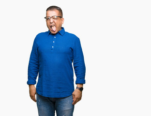 Fototapeta premium Middle age arab man wearing glasses over isolated background sticking tongue out happy with funny expression. Emotion concept.