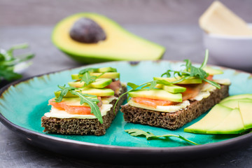 Ready-to-eat bruschettas with salmon, butter, avocado and arugula on a plate
