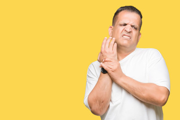 Middle age arab man wearig white t-shirt over isolated background Suffering pain on hands and fingers, arthritis inflammation