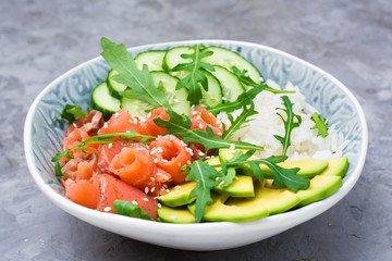 Salmon poke with  avocado, arugula and cucumber in a bowl