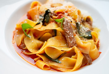 pasta papardelle with beef on a white plate close-up