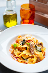cooked pasta papardelle with beef on a white plate in the restaurant