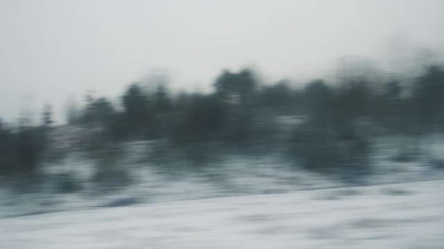 Fast cinematic view through the window of a fast TGV ICE train over the French hills and villages early in the morning on the cold snowy winter - 4K UHD footage