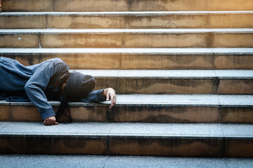 The poor homeless person lay at the public staircase. No place to go.