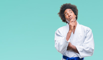 Afro american man wearing karate kimono over isolated background with hand on chin thinking about question, pensive expression. Smiling with thoughtful face. Doubt concept. © Krakenimages.com