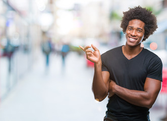 Afro american man over isolated background with a big smile on face, pointing with hand and finger to the side looking at the camera.