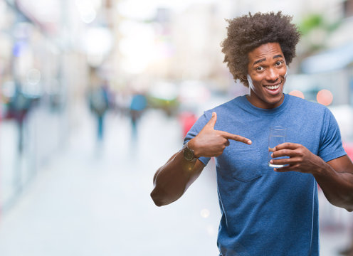 Afro american man drinking glass of water over isolated background very happy pointing with hand and finger