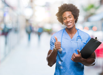 Afro american surgeon doctor holding clipboard man over isolated background happy with big smile...