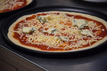 Pizza roh belegt mit Käse und Tomatensauce