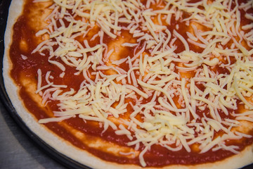 Pizza roh belegt mit Käse und Tomatensauce