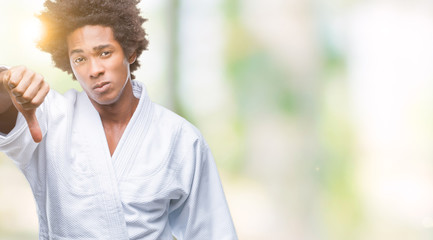 Afro american man wearing karate kimono over isolated background looking unhappy and angry showing rejection and negative with thumbs down gesture. Bad expression.