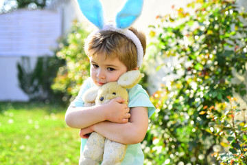 Cute little child wearing bunny ears on Easter day. Boy holding toy rabbit ang hug. Love and care concept. Kids hug embrace.