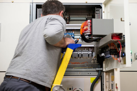 &eacute;lectricien sur un escabeau v&eacute;rifiant une installation &eacute;lectrique