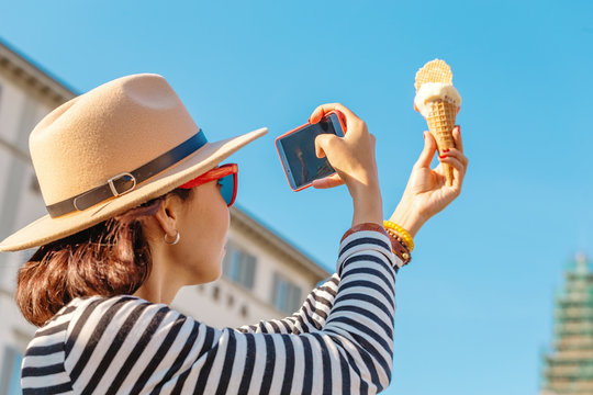The girl takes pictures of ice cream on her smartphone