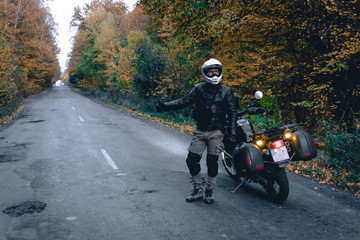 Biker man in leather jacket and black tourist motorcycle with side bags. wallpaper concept, enduro advetnture, space for text, autmn season, problems on the road accident