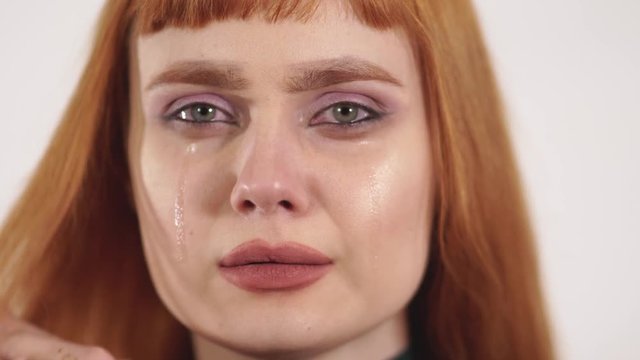 Young beautiful crying female remove tears from her face and showing pain, upset, sedness,