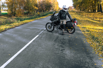 Fototapeta premium Rowerzysta mężczyzna w skórzanej kurtce i czarny motocykl turystyczny z bocznymi torbami. koncepcja tapety, reklama enduro, miejsce na tekst, sezon świąteczny