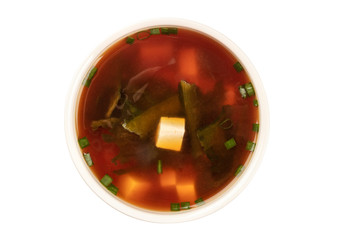 A photo of a bowl of miso soup with tofu, scallions, and wakame seaweed, shot from the top, isolated on a white background with a clipping path