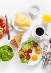 healthy breakfast flat lay. fried eggs, avocado, tomato, toasts and coffee