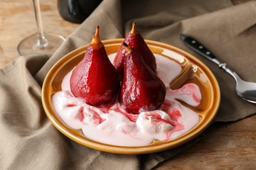 Plate with ice cream and sweet pears stewed in red wine on wooden table