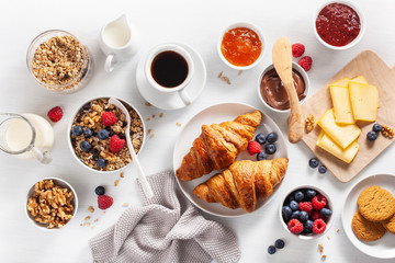 healthy breakfast with granola, berry, nuts, croissant, jam, chocolate spread and coffee. Top view