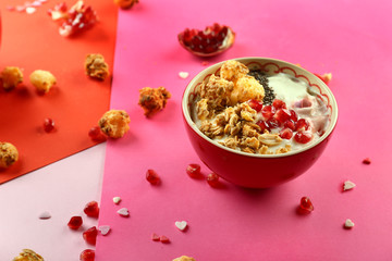 Tasty granola with yogurt and pomegranate seeds in bowl on color background