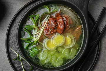 Tasty Chinese soup in bowl on grey table
