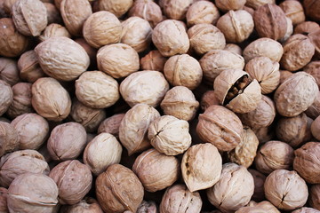 A lot of walnuts in a pile. Hard brown shell.