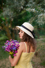 Fototapeta premium Woman with flowers in hands, wearing white hat.