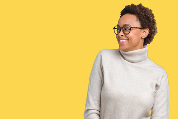 Young beautiful african american woman wearing glasses over isolated background looking away to side with smile on face, natural expression. Laughing confident.