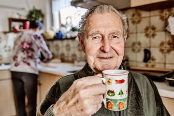Senior trinkt in der Küche Kaffee während seine Frau kocht
