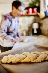 Seniorin backt in der Küche ein Brot, Hefezopf, 