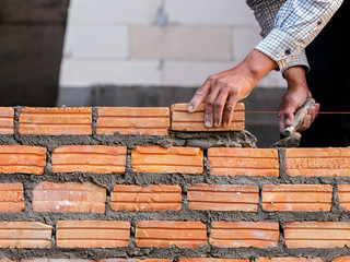 Construction worker laying bricks on exterior walls in construction site