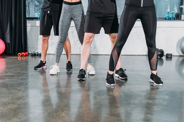 low section of young men and women in sportswear training together in gym