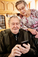 Senior, Seniorin, Seniorenpaar surft gemeinsam auf einem Smarphone im Internet