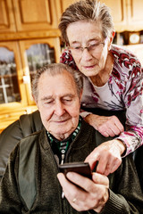 Senior, Seniorin, Seniorenpaar surft gemeinsam auf einem Smarphone im Internet