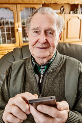 Senior surft zuhause mit einem smart phone im Internet