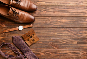 Stylish male shoes with accessories on wooden table