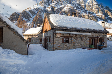 Panoramic view of the sunny snow-covered landscape of the village of Crampiolo, above the Alpe Devero in Piedmont, Italy.